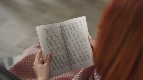 redhead woman flips book pages reading story in english