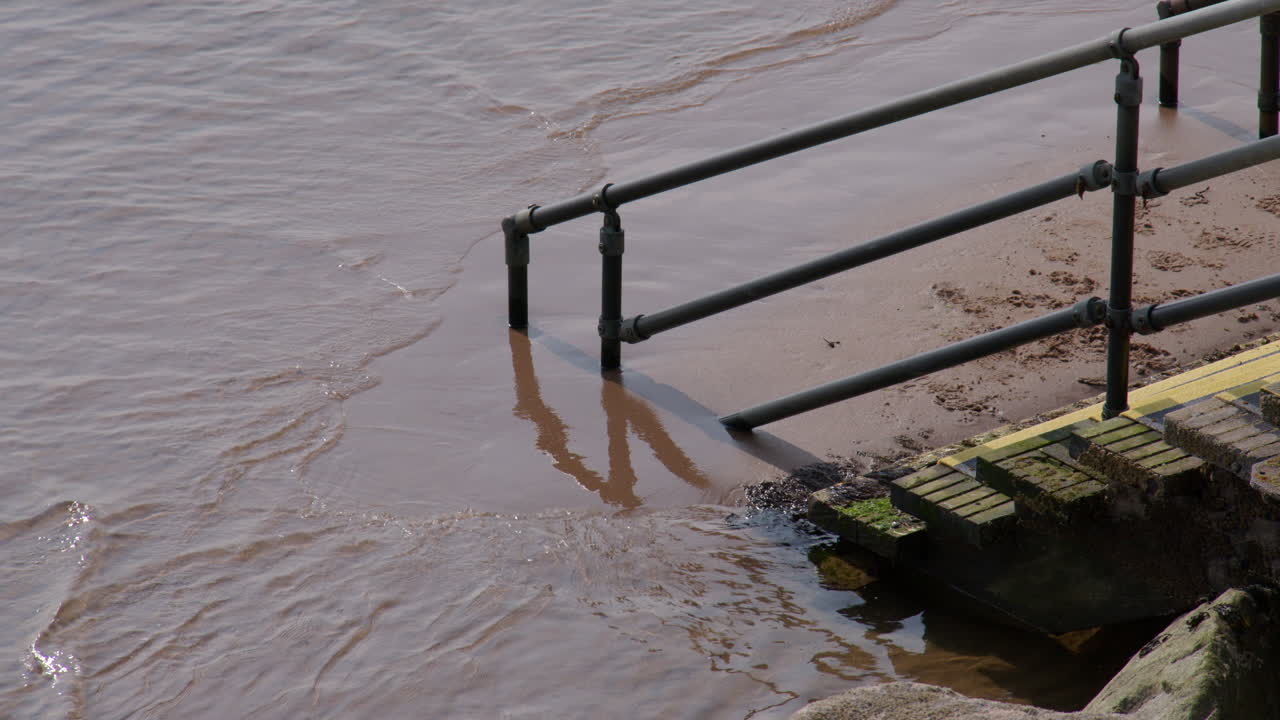 Mid shot of stairs with handrail disappearing into the sand and sea at Montrose beach