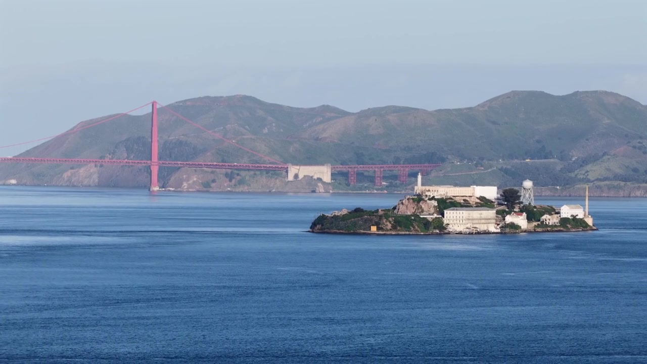 San Francisco Körfezi, Kaliforniya, Amerika Birleşik Devletleri'nde hafif sabah sisi altında uzakta Alcatraz Adası ve Golden Gate Köprüsü. Geniş hava görüntüsü. Sinematik drone çekimi. Yazın güneşli bir gün