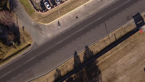 Aerial-top-down-shot-of-cyclist-riding-bike-on-street-of-La-Plata-at-sunset-in-Buenos-Aires---Tracking-shot