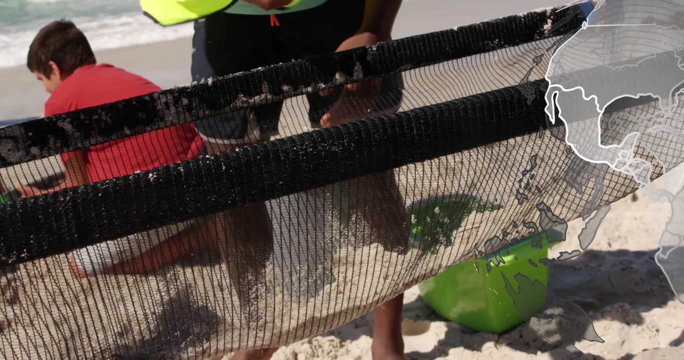 Teenage boy scooping sand into net held by neon vest man, team shaking for environmental sampling