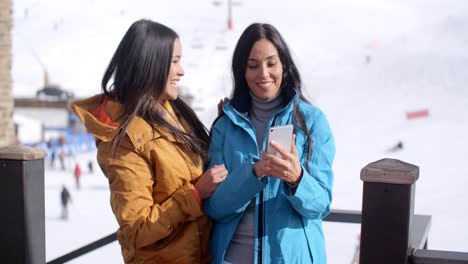 Dos-Mujeres-Jóvenes-Sonrientes-Revisando-Un-Teléfono