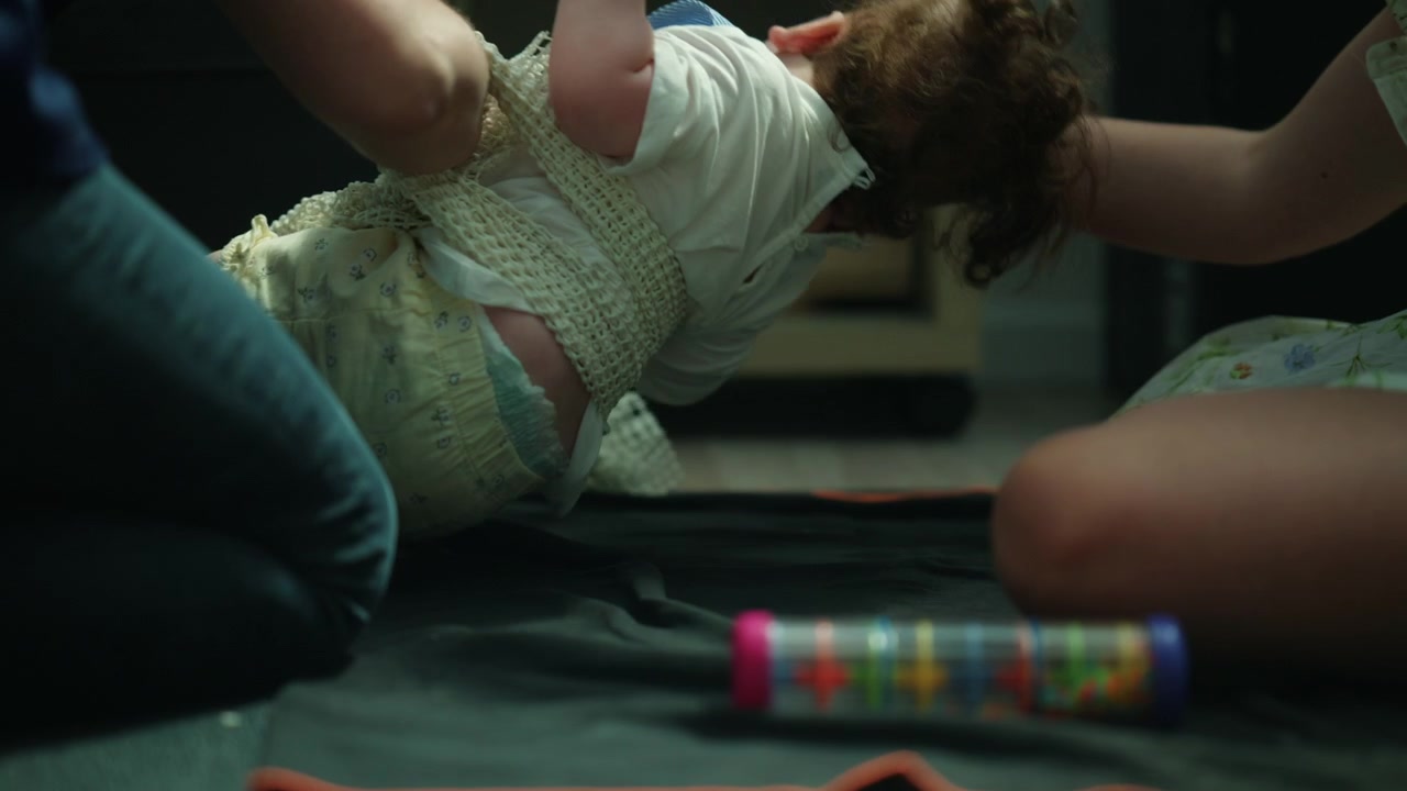 Baby performing physical therapy with therapist guiding arm movements on mat. Focus on medical care and rehabilitation