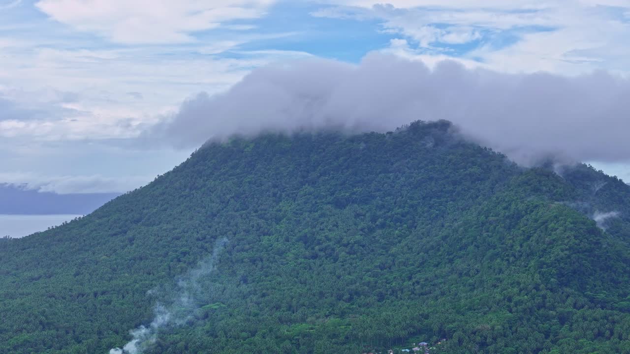 Rekaman udara Gunung Paco di Surigao del Norte, Filipina, menampilkan medan pegunungan yang diselimuti awan dan lereng berhutan. Tampilan drone menyoroti lanskap alam dan ketinggian di bawah langit mendung