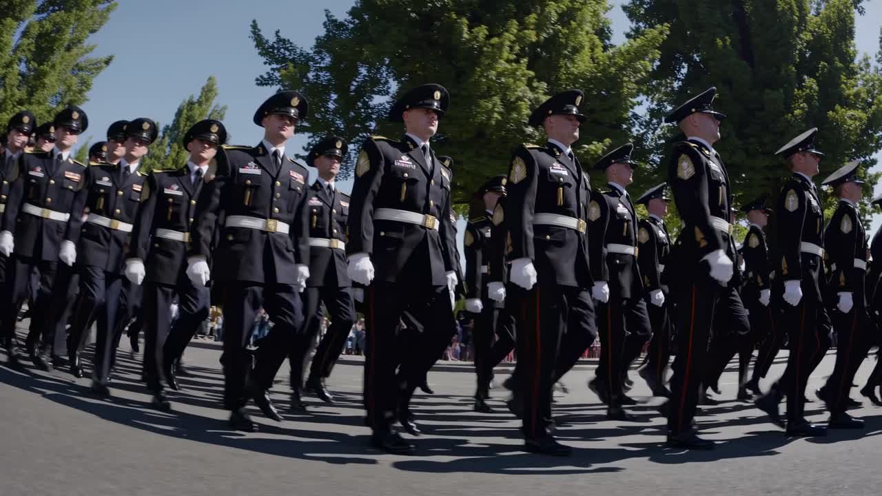 Video con angolazione bassa di soldati in uniforme che marciano in formazione lungo una strada alberata