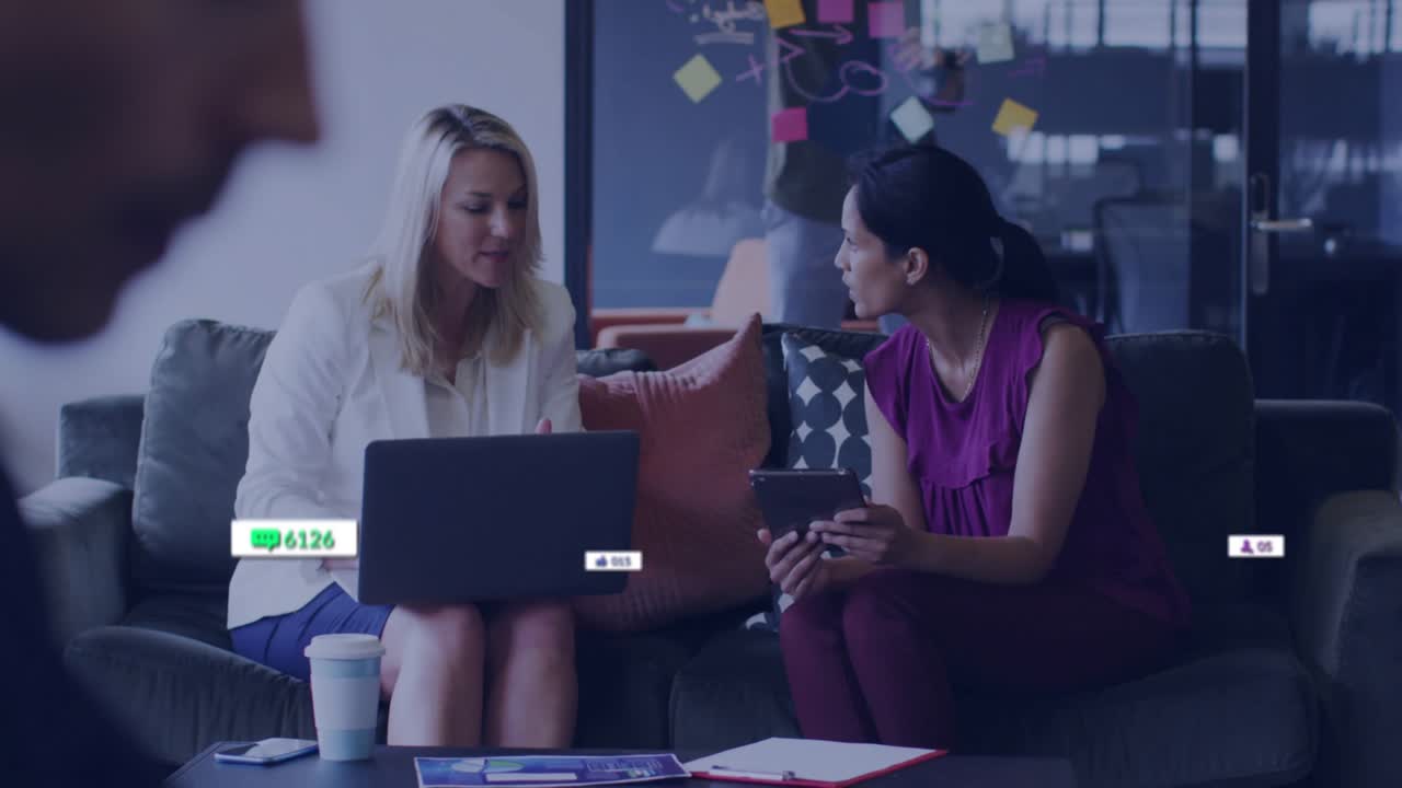 Coworkers opening laptop and tapping tablet generating floating engagement metrics for marketing