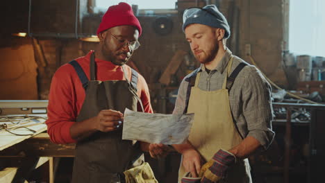 two blacksmiths discussing technical drawing in workshop