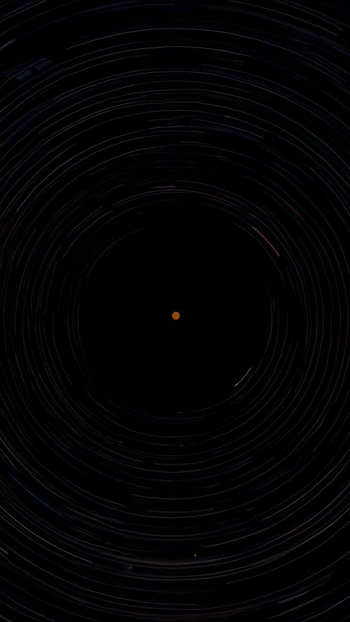 Video verticale: apertura dell'otturatore, struttura che registra una rotazione polare attorno a un punto arancione e scie
