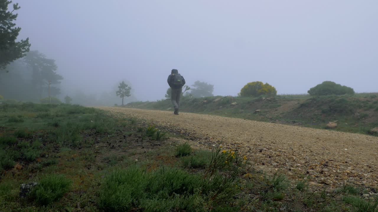 테문테인의 추운 날 안개 속에서 배낭을 메고 길을 오르는 남자