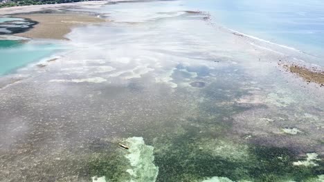 Aerial-drone-reverse-over-stunning-ocean-with-coral-reefs-and-sand-bars-at-low-tide-with-crystal-clear-water-on-tropical-island-paradise