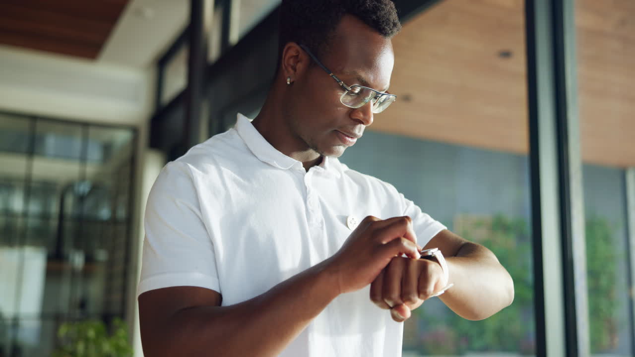 Young Black Man Interacting with Smartwatch in Modern Setting