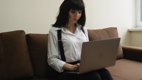 joven usando una computadora portátil en casa sentada en el sofá