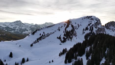 Toma-Aérea-De-Un-Dron-Que-Revela-La-Luz-Del-Sol-Del-Amanecer-Detrás-De-La-Montaña-Nevada-De-Gulmen-En-Suiza