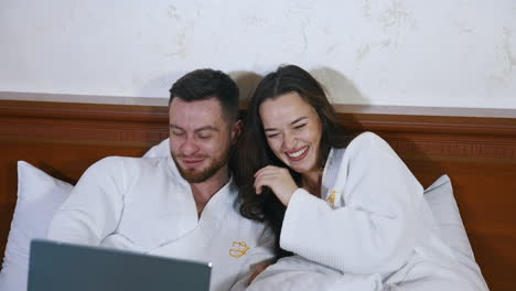 young couple at hotel room. happy couple in bathrobes in bedroom at hotel