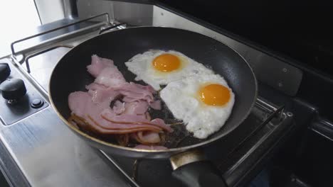 bacon and eggs frying an a pan on a gas cooker in a campervan or motorhome