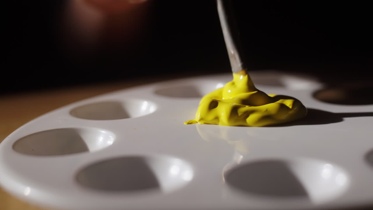 Artist mixing yellow paint on a palette
