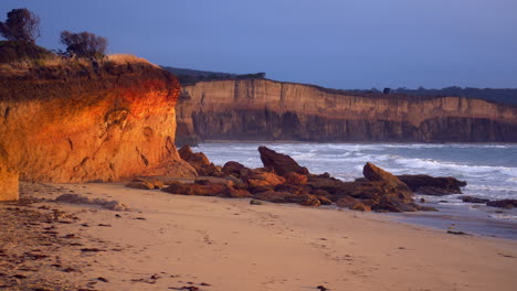 eroded golden sandstone seaside cliffs during sunset, pan right