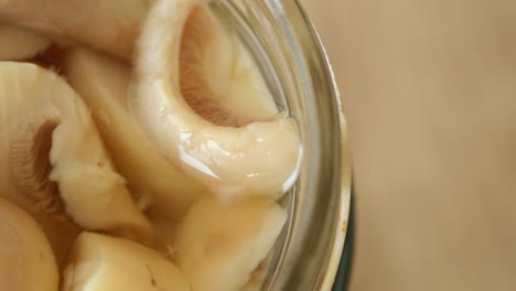 close up of canned white mushrooms in a glass jar