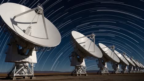 radio telescopes under a star-streaked night sky