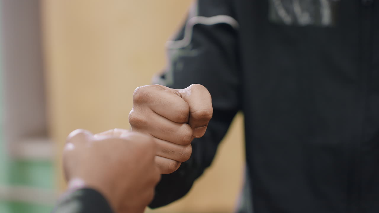 Close up partial view of friends playing hand trick game with focus on clenched fist gesture, capturing playful interaction, concentration, and dynamic motion during friendly activity indoors