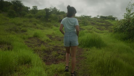 Cinematic-slow-motion-shot-of-an-Indian-young-girl-who-walks-gracefully-through-the-lush-green-expanse-of-an-Indian-forest