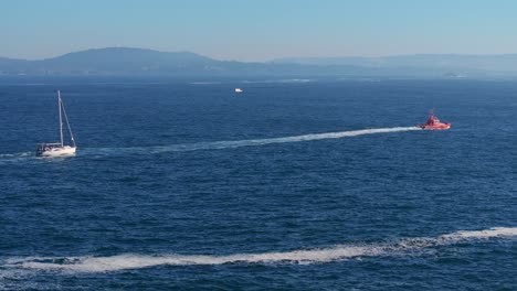 Lifeboat And Yacht Cruising In The Ocean With Calm Waves At Summer. - aerial shot