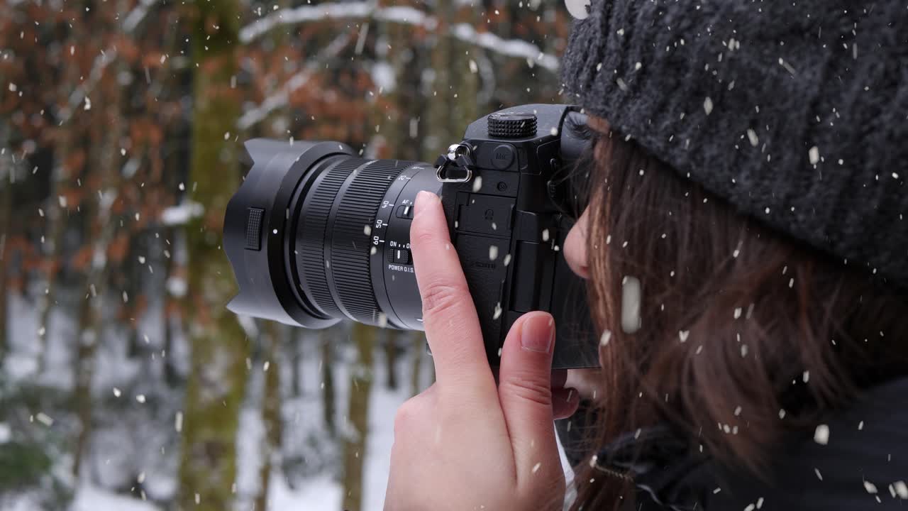 mujer tomando fotos del bosque de invierno durante las fuertes nevadas, vista de cerca