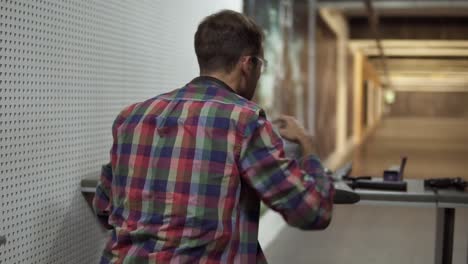 Rare-View-Of-A-Man-In-Indoors-Shooting-Range-Putting-On-Protective-Headphones