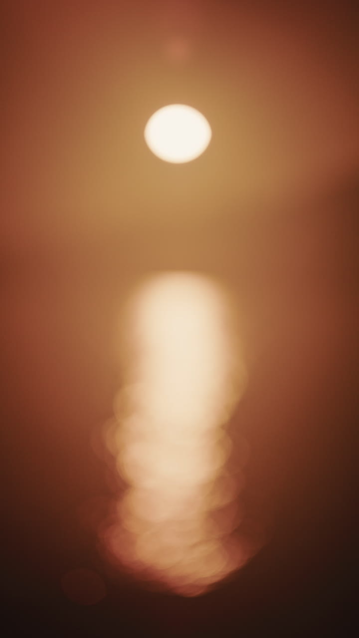 Foto abstrata e fora de foco do sol e seu reflexo no mar. Vertical