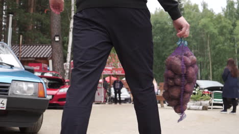 man carrying a bag of potatoes at an outdoor event