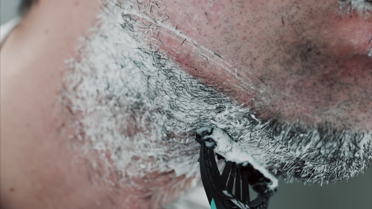 Primo piano di un uomo che si rade la barba con un rasoio