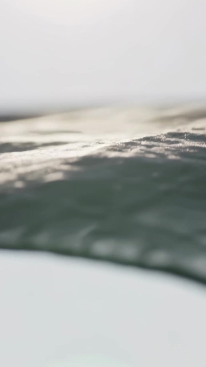 Vertical video: Camera tilting, quilt shifting upward in bedroom, seam catching window light