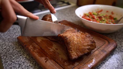 person cutting roast meat on wooden board