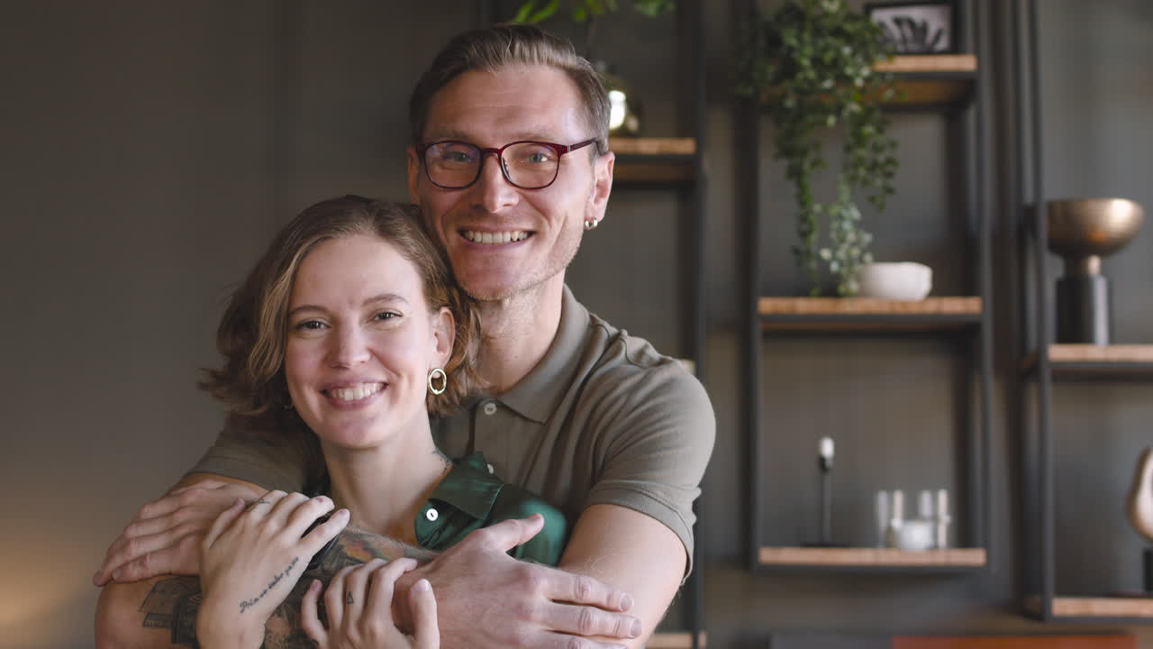 Portrait Of A Happy Couple Smiling At Camera At Home While Man Embracing Woman From Behind 1