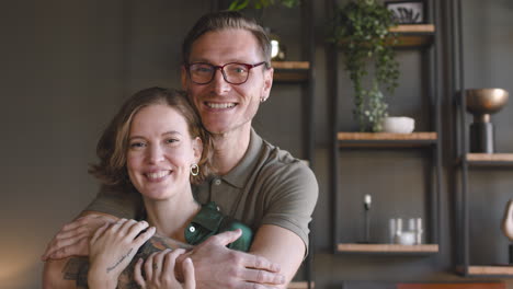 retrato de una pareja feliz sonriendo a la cámara en casa mientras el hombre abraza a la mujer por detrás 1