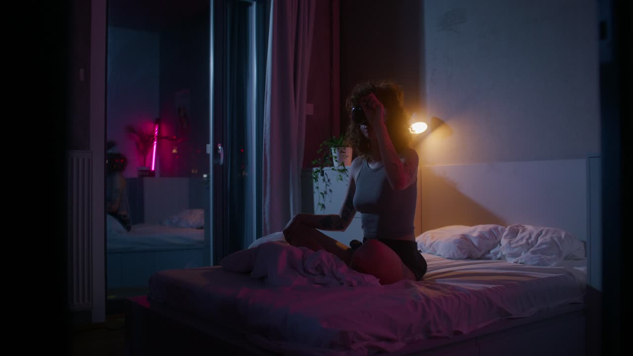 Donna che indossa un visore VR in una camera da letto di notte