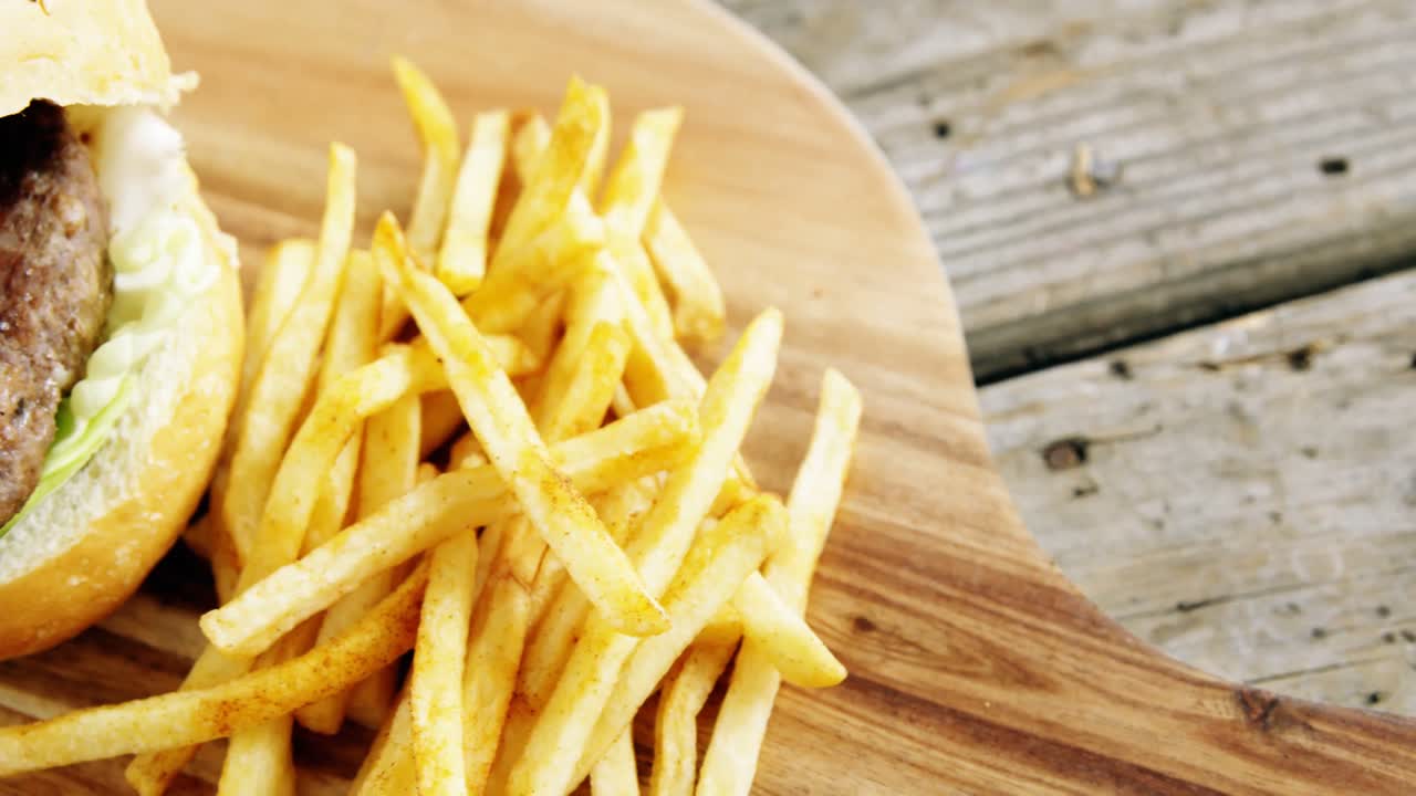 Hamburger and french fries on chopping board