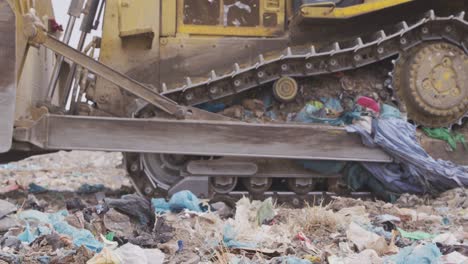 vehículos que limpian la basura apilada en un vertedero lleno de basura