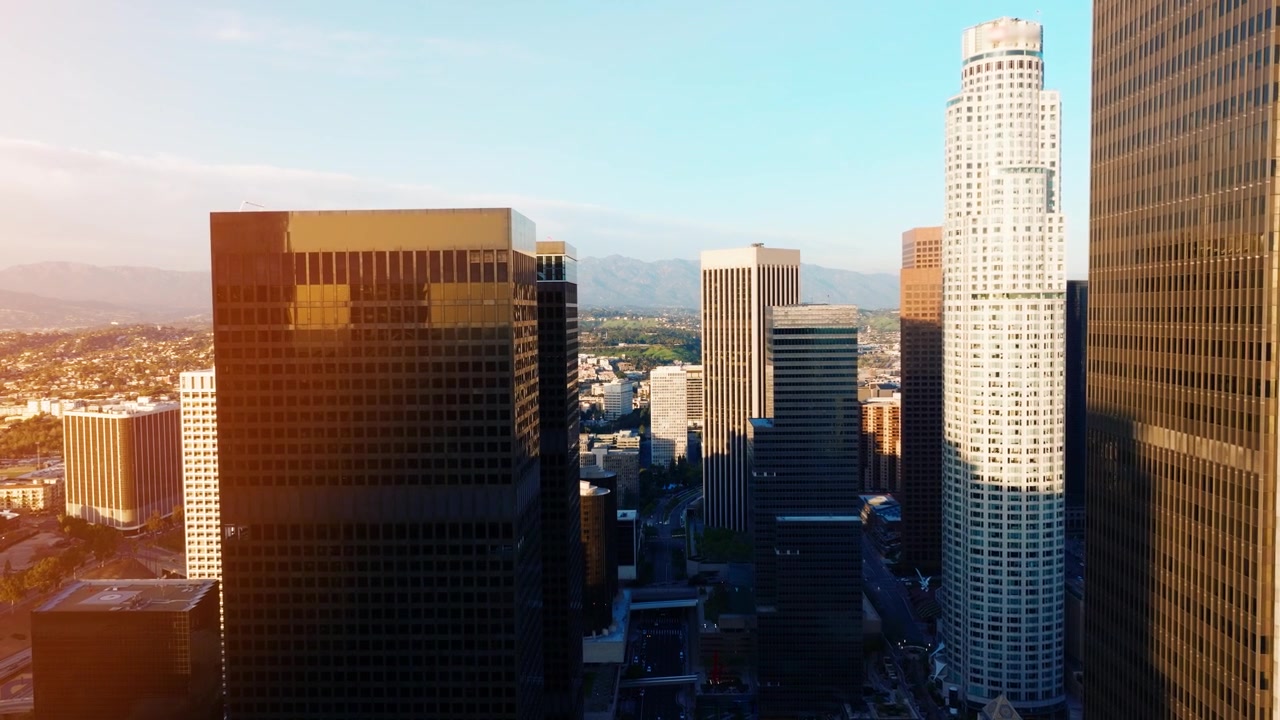 Vista del centro di Los Angeles che mostra la congestione del traffico durante l'ora di punta. Grattacieli e infrastrutture cittadine sono visibili sotto il bagliore del tramonto sull'area metropolitana.