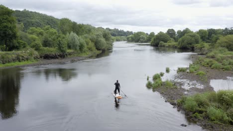 Un-Hombre-Solitario-Rema-En-Un-Pequeño-Y-Tranquilo-Río-En-El-Campo-Rural