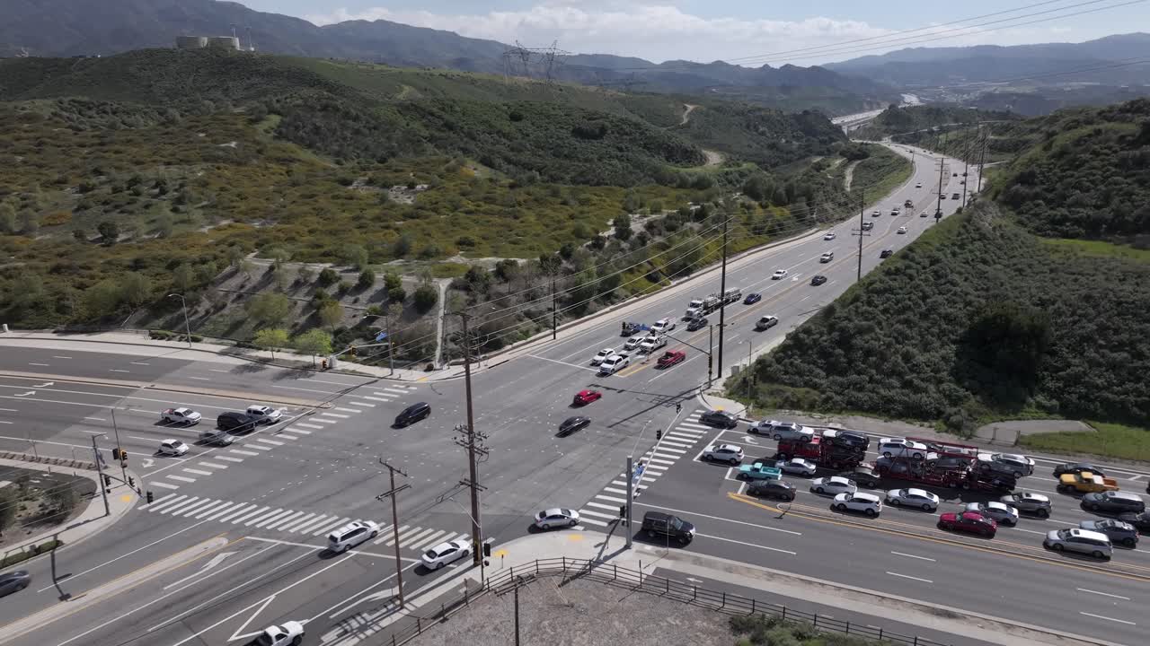 vista aérea de coches que conducen a través de la intersección entre campos verdes y montañas