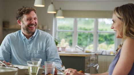 Family-Sitting-Around-Table-At-Home-Enjoy-Meal-Together