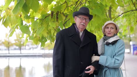elderly couple standing outdoors in a park by the water