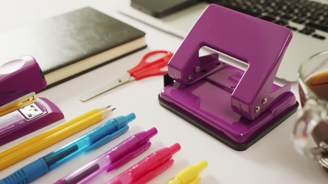 video de varios bolígrafos coloridos, cuadernos, tijeras y puñetazos en el escritorio