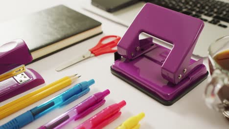 video of diverse colorful pen, notebook, scissors and punch lying on desk