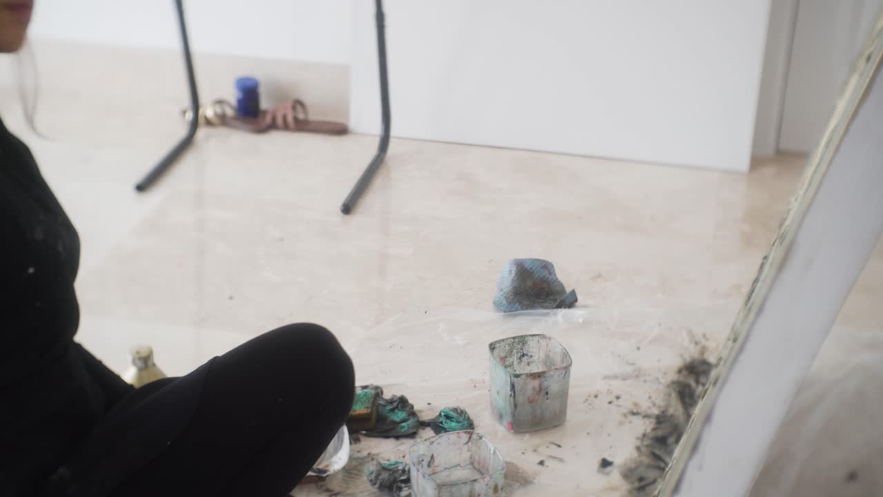 artista latina haciendo una pintura abstracta sobre lienzo en su taller - plano medio