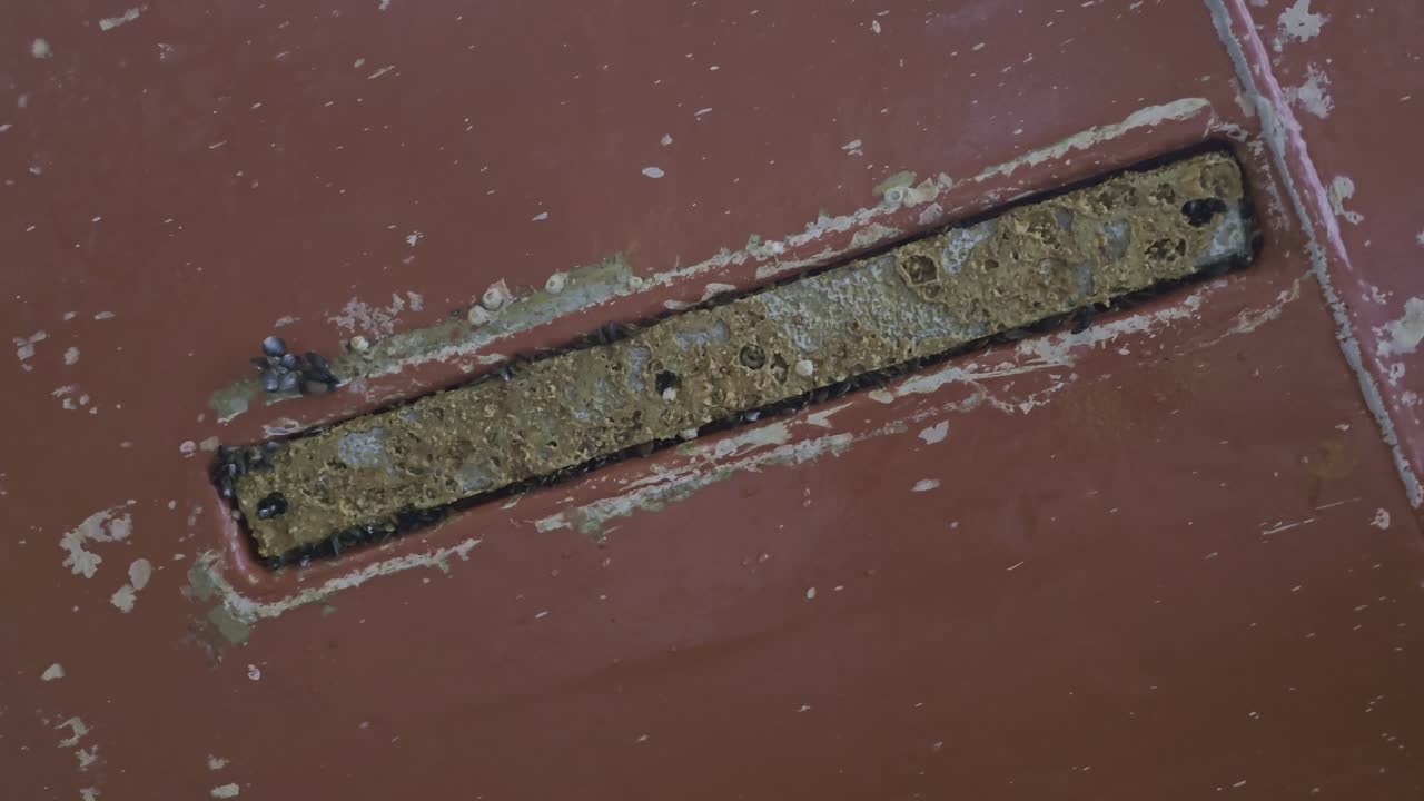 Zinc anode flush with ship hull appears worn and dirty during inspection in drydock. Anti corrosion use.
