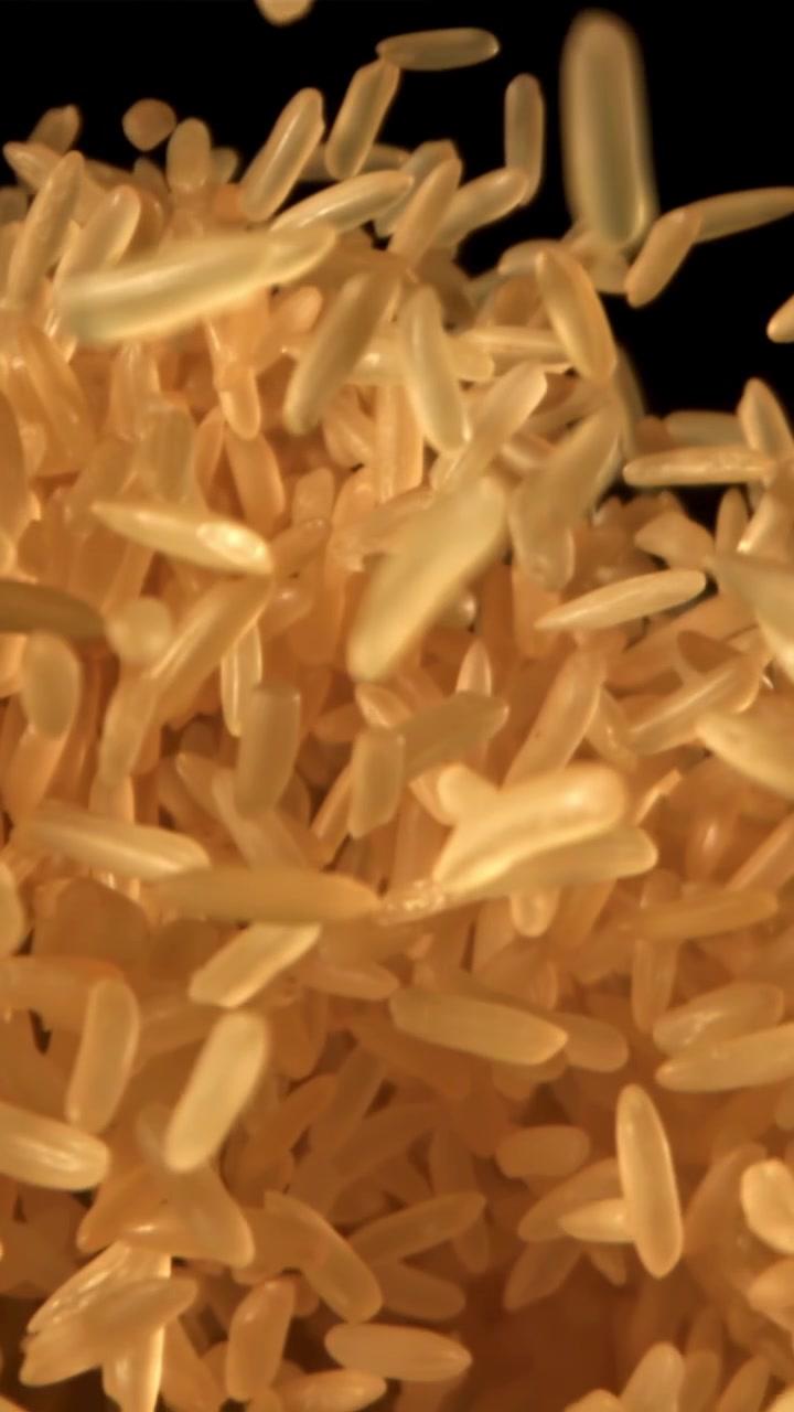 Golden Rice Grains Falling in Slow Motion on Black Background