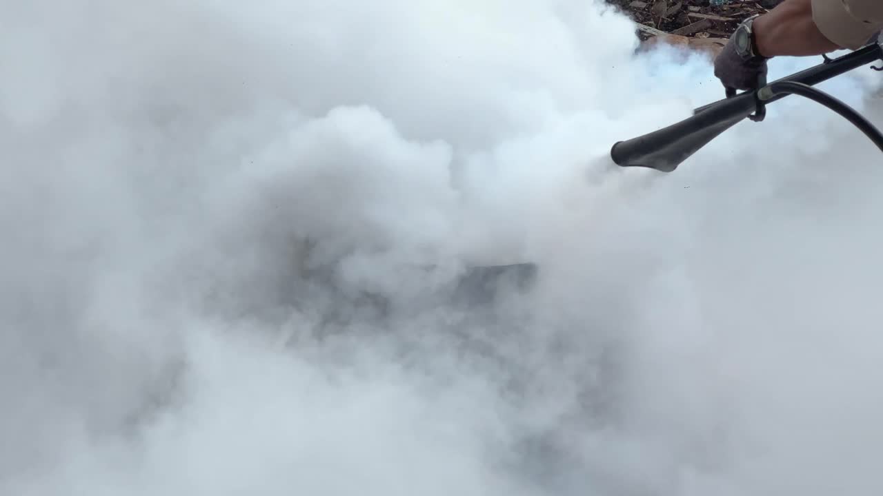 A burning metal drum with visible flames in an outdoor environment extinguished by CO2 fire extinguisher type. Fire emergency simulation. Fire fighting training.