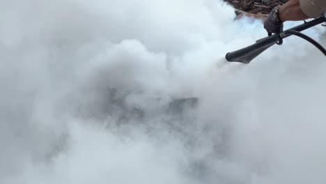 a burning metal drum with visible flames in an outdoor environment extinguished by co2 fire extinguisher type. fire emergency simulation. fire fighting training.